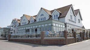 Una hilera de edificios blancos con fachada verde, que incluye un restaurante llamado "The Botany Bay".