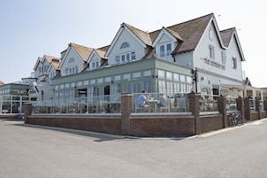 A row of white buildings with a green facade, including a restaurant named "The Botany Bay."