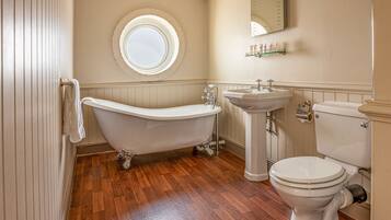A bathroom with a freestanding bathtub, a pedestal sink, and a toilet.