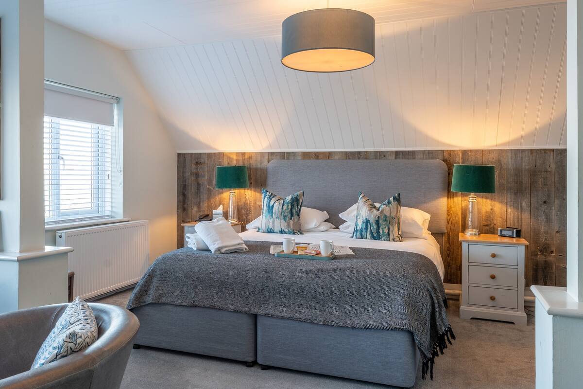 A bedroom with a bed, bedside tables, a chair, and a window with blinds.