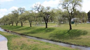 Ein Park mit einem gepflasterten Weg, einem kleinen Bach und Bäumen.