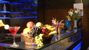 A bar area with a glass counter, a martini glass, a basket of fruits, and a vase with flowers. - 19Belo Cabana (Calangute)
