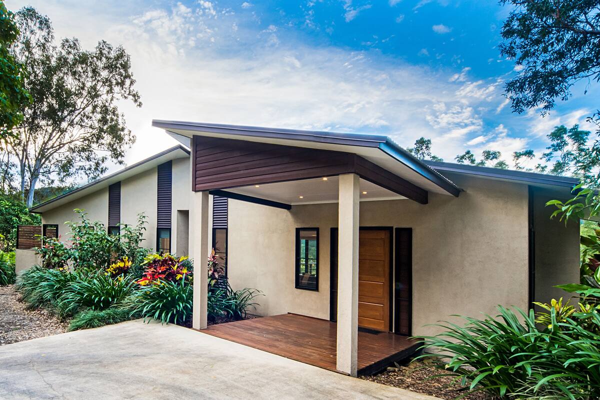 A modern house with a covered porch, a wooden deck, and a landscaped garden.