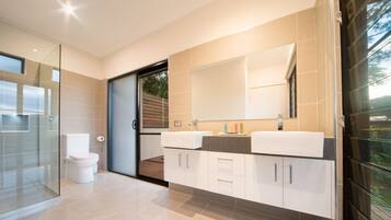 A modern bathroom with a glass shower enclosure, a toilet, and a double sink vanity with cabinets.