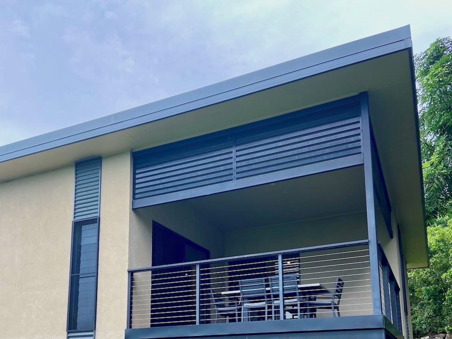 A modern building with a balcony featuring a table and chairs.