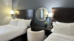 Une chambre d’hôtel avec deux lits, un miroir rond, des lampes de chevet, une petite table avec un téléphone et une chaise.