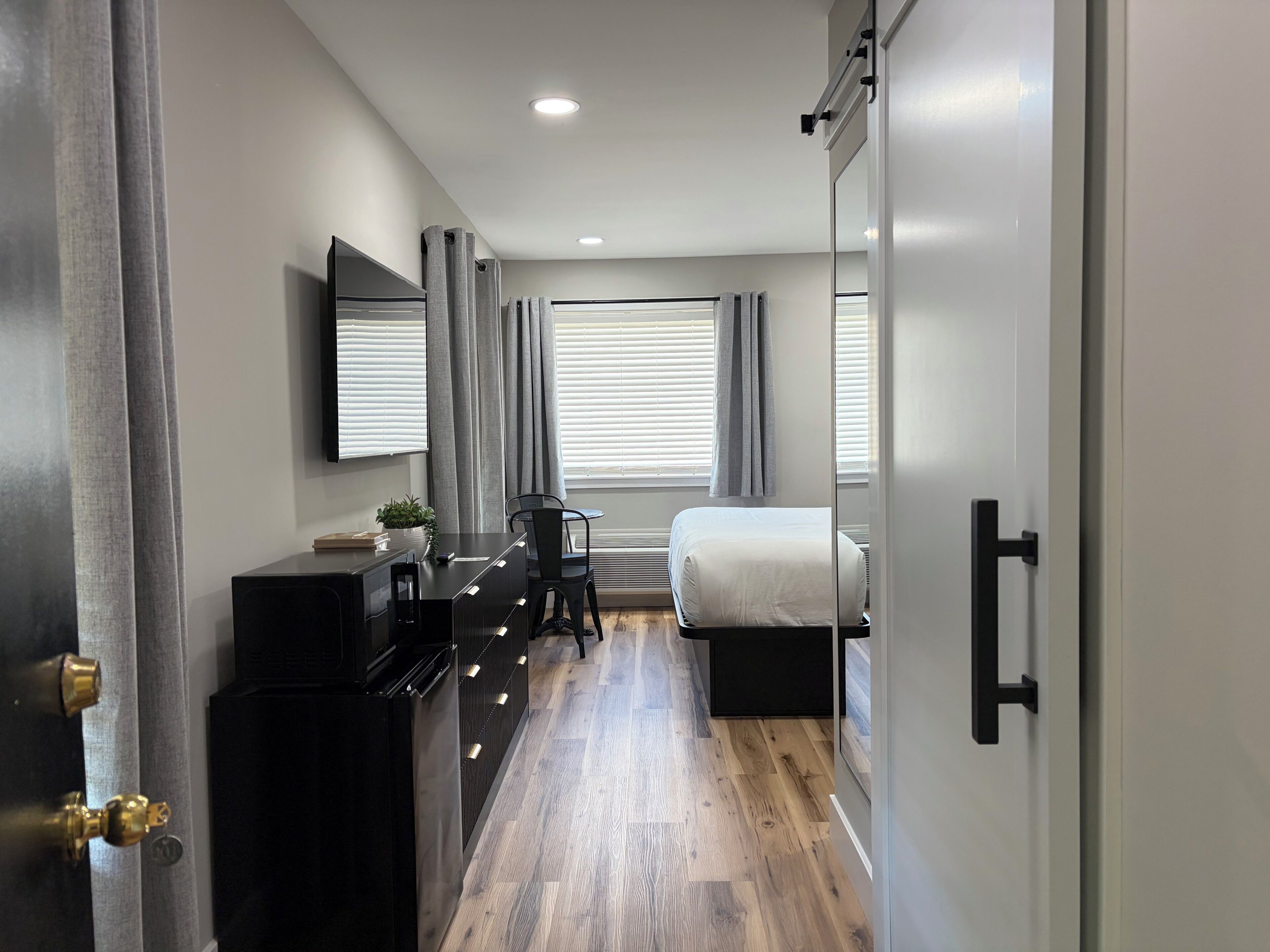 Un dormitorio moderno con cama, mesita de noche y escritorio con silla.