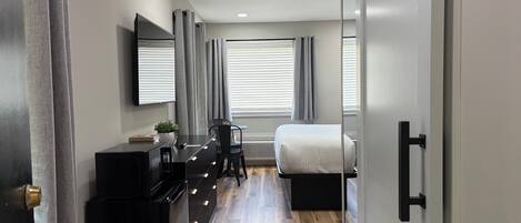 Un dormitorio moderno con cama, mesita de noche y escritorio con silla.