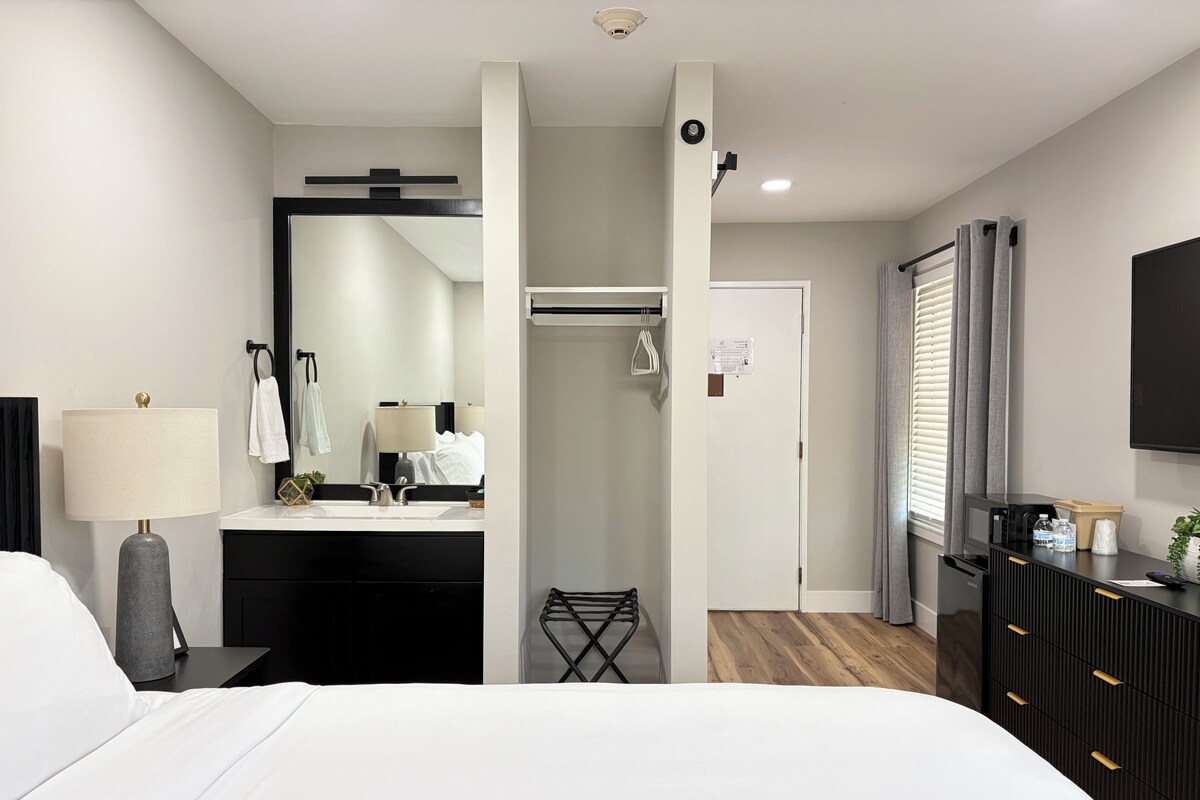 Une chambre d’hôtel moderne équipée d’un lit, d’une salle de bain avec un miroir, un lavabo et une armoire.