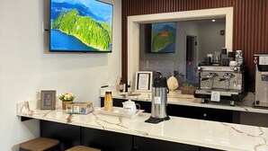 Une cuisine moderne dotée d’un plan de travail en marbre, de tabourets de bar, d’une machine à café et d’un grand téléviseur à écran plat diffusant une scène de la nature.