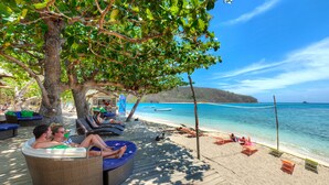Eine Strandlounge mit Korbmöbeln und Blick aufs Meer.