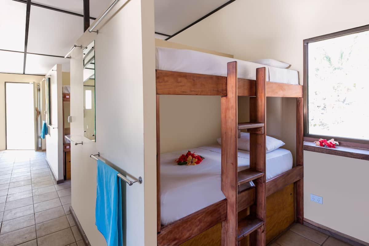 Een slaapkamer met stapelbed, raam en een blauwe handdoek aan de deur.