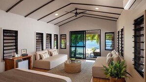 Ein modernes Wohnzimmer mit Sofa, Couchtisch und Bett. Große Fenster bieten einen Blick ins Freie.