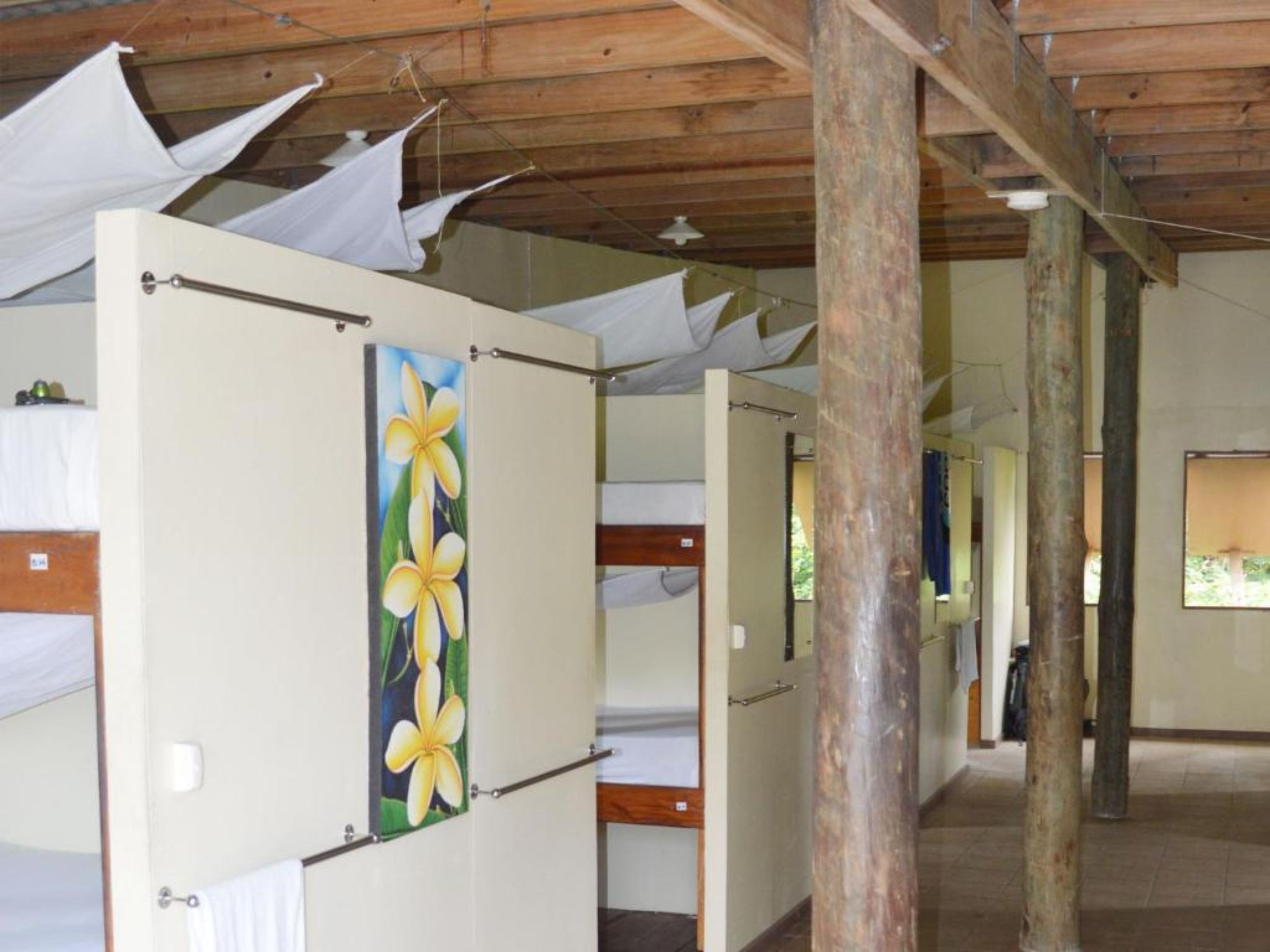 Una fila de habitaciones individuales con vigas de madera y un ventanal grande.