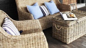 Wicker furniture with cushions, a magazine, and a tripod.