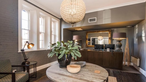 A modern living room with a round table, a potted plant, and a chandelier.