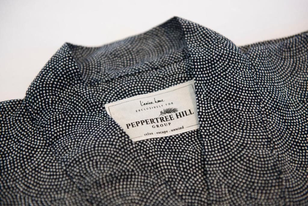 Ein Etikett an einem Kleidungsstück mit dem Text 'Peppertree Hill Group' und dem Slogan 'relax. escape. unwind.'