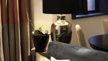 Una stanza con un divano, una lampada nera, una pianta in vaso e una finestra con tende.
