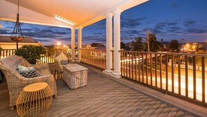 A covered outdoor area with wicker furniture, a round table, and a hanging light fixture.