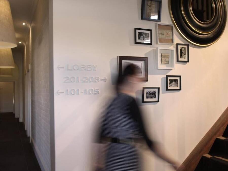 A hallway with a staircase, a wall with framed pictures, and directional signs for the lobby.