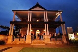 A hotel with a covered entrance, columns, and a balcony.