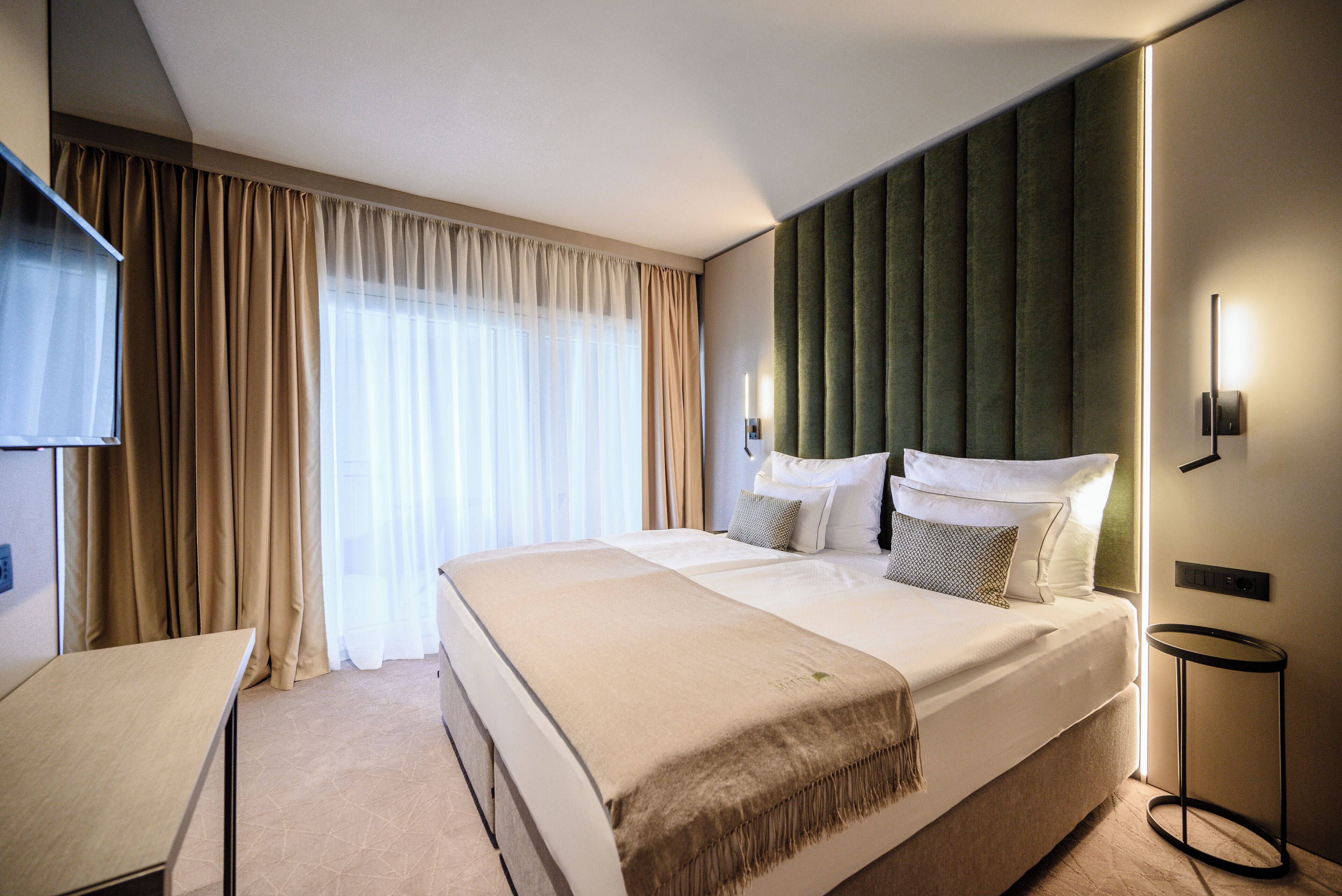 Una habitación de hotel moderna con una cama grande, un escritorio y una televisión.