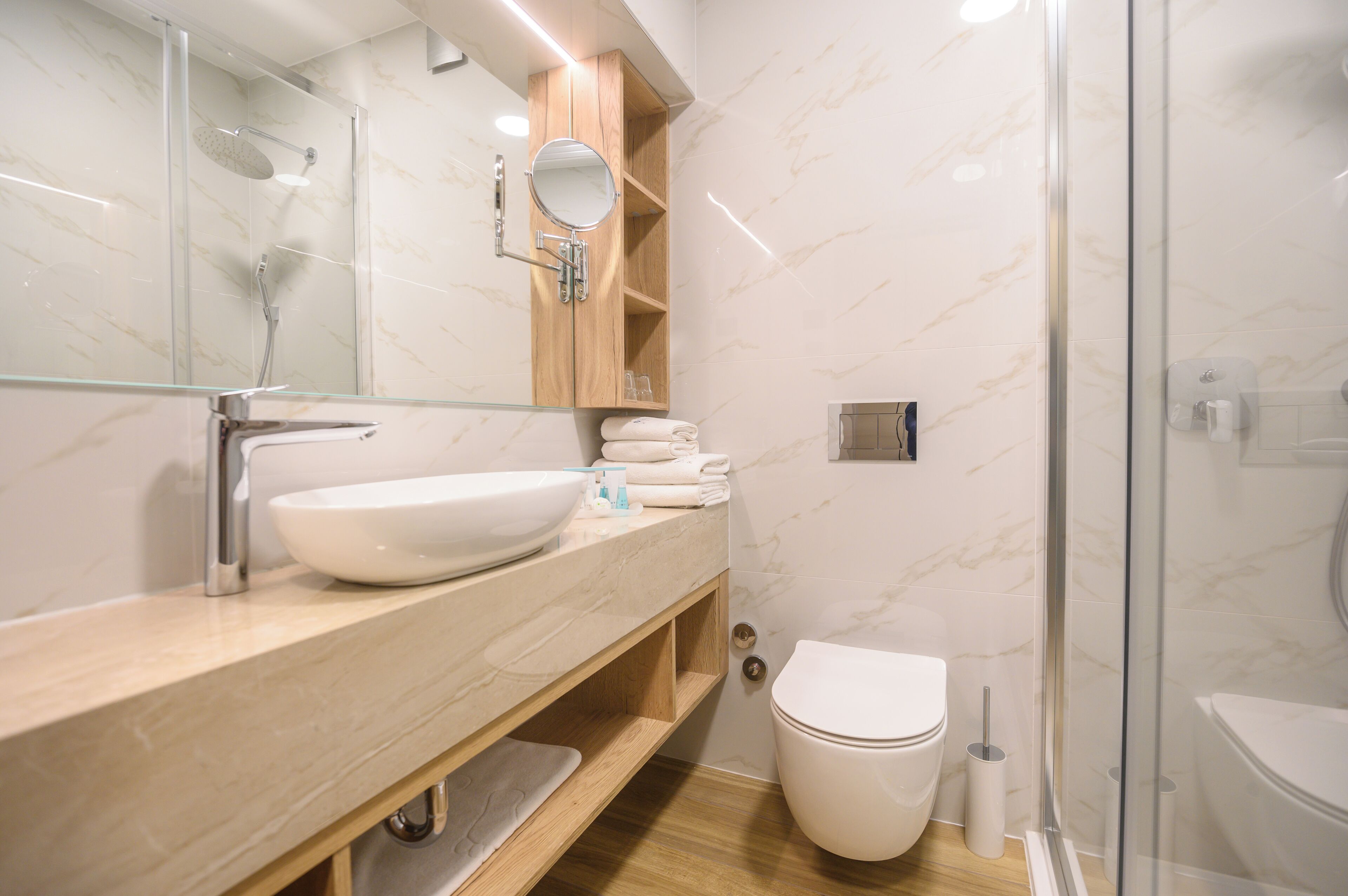 A modern bathroom with a glass shower enclosure, a white sink, and a wooden vanity.