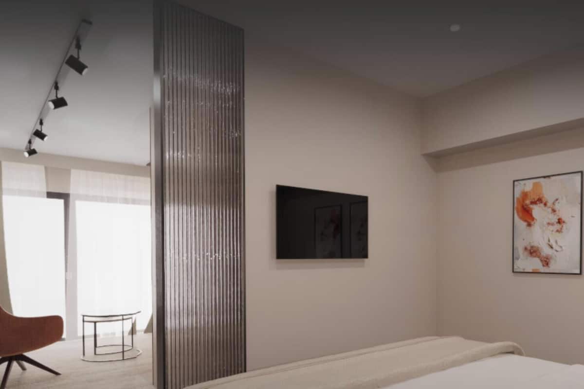 Une chambre d’hôtel moderne, équipée d’un lit, d’une chaise et de deux tableaux abstraits accrochés au mur.