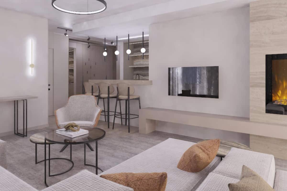 Un salon moderne doté d’une cheminée, d’un coin bar et d’un espace détente avec des canapés et une table basse.