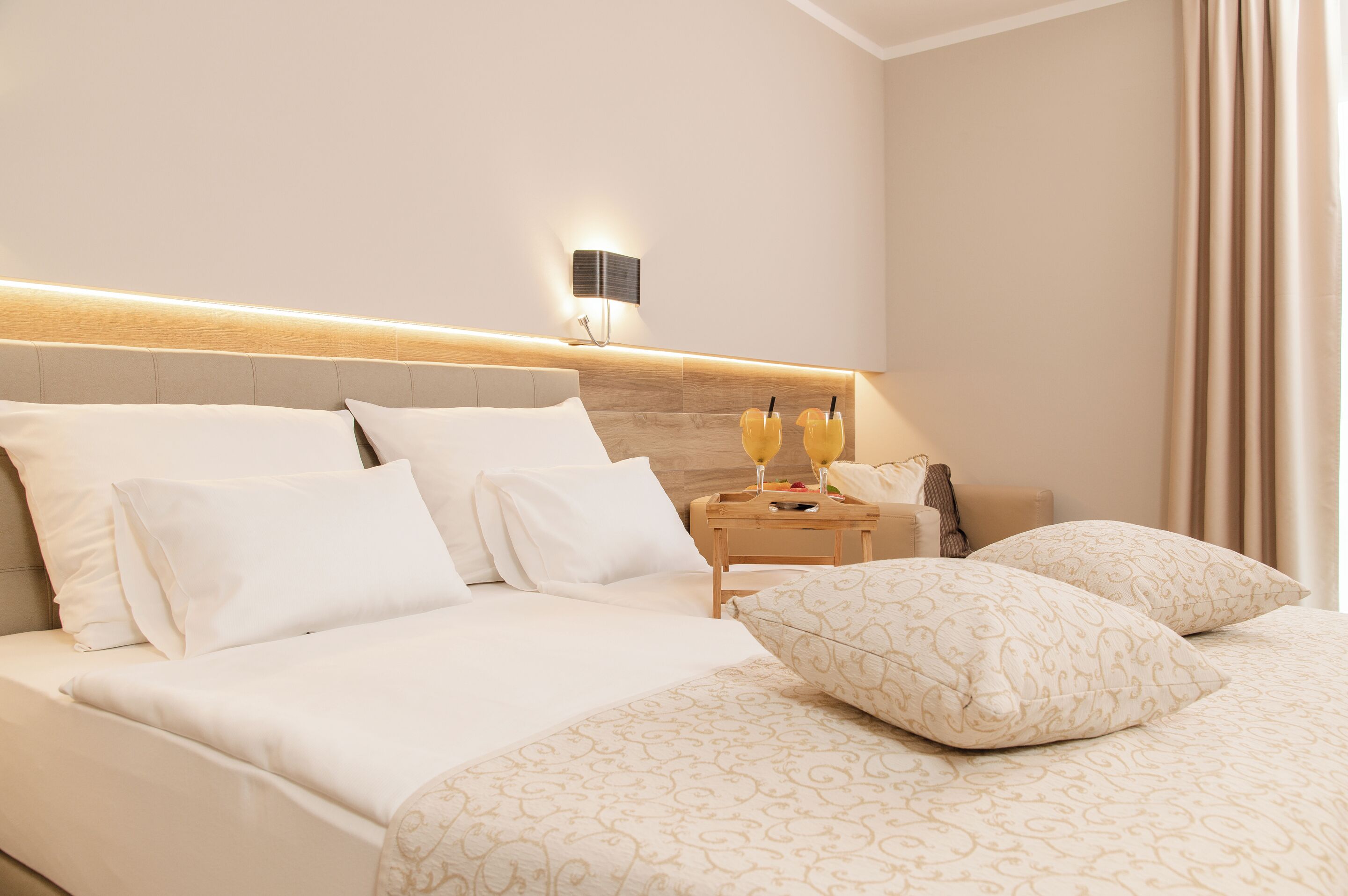 Una habitación de hotel con una cama grande, una mesita de noche con lámpara y una lámpara de pared.