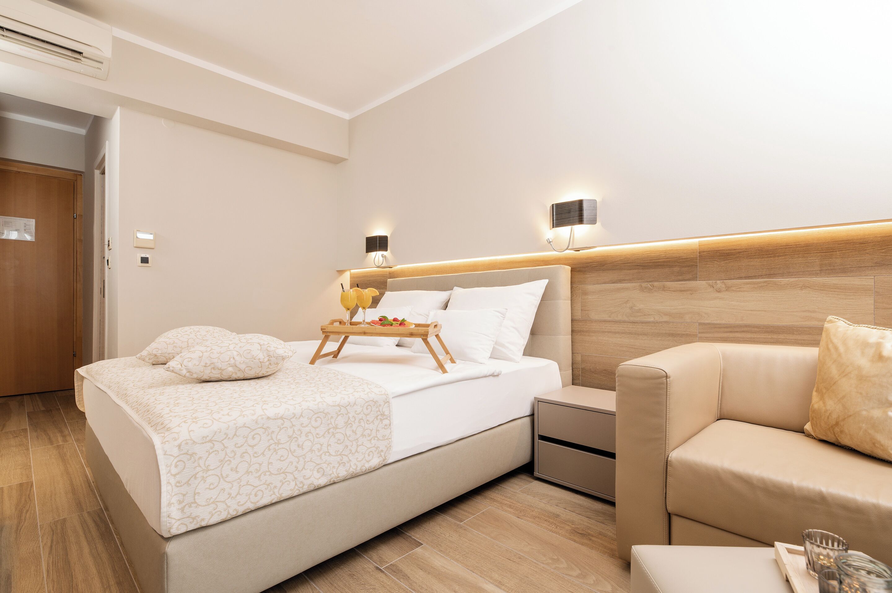 Ein modernes Hotelzimmer mit einem großen Bett, Nachttischen, einer Couch und einem Holz-Kopfteil.