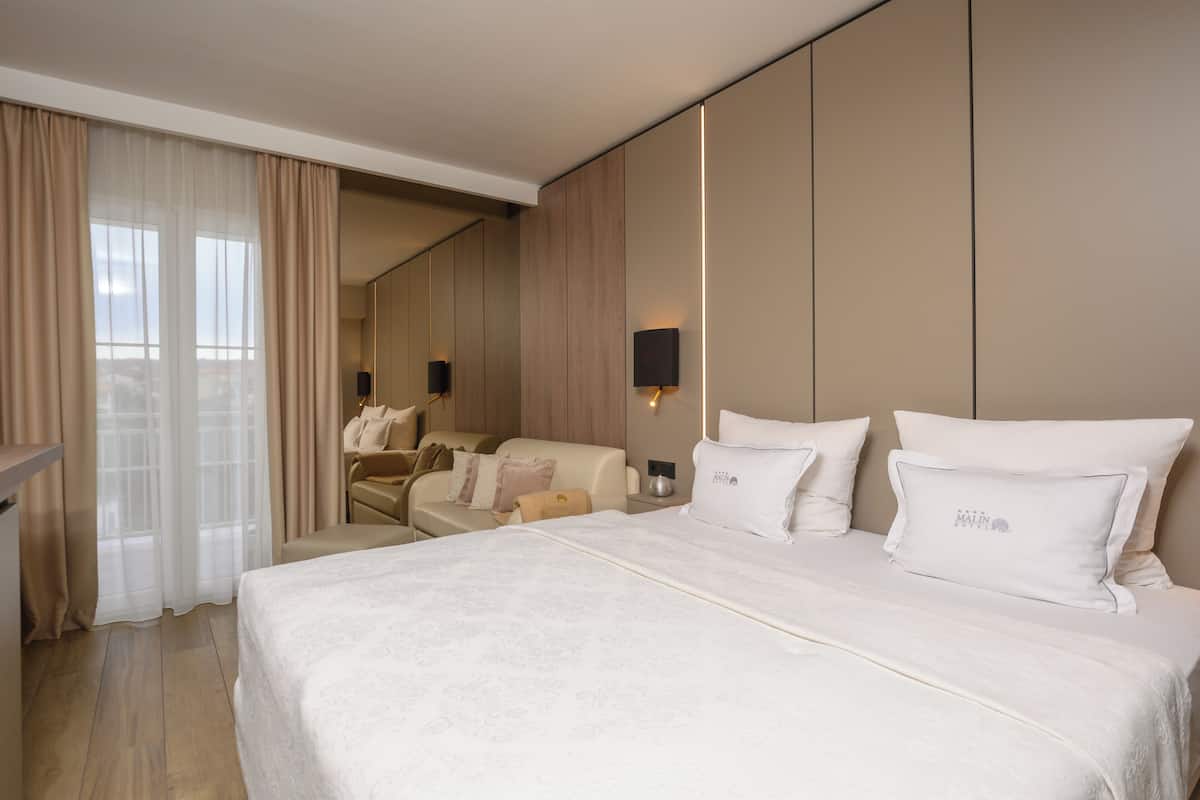 Une chambre d’hôtel avec un grand lit, un canapé, un bureau et un miroir.