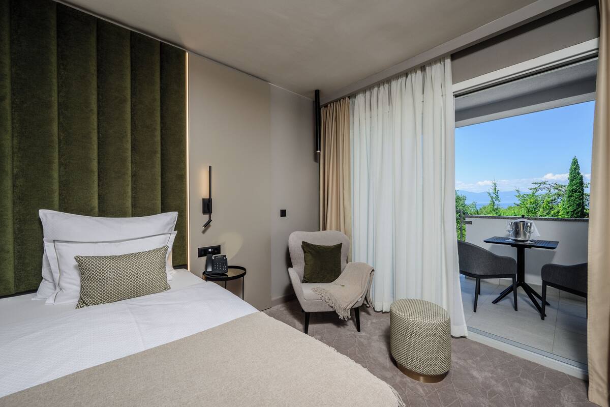 Une chambre d’hôtel avec un lit, une chaise, une petite table et un balcon équipé d’une table et de chaises.