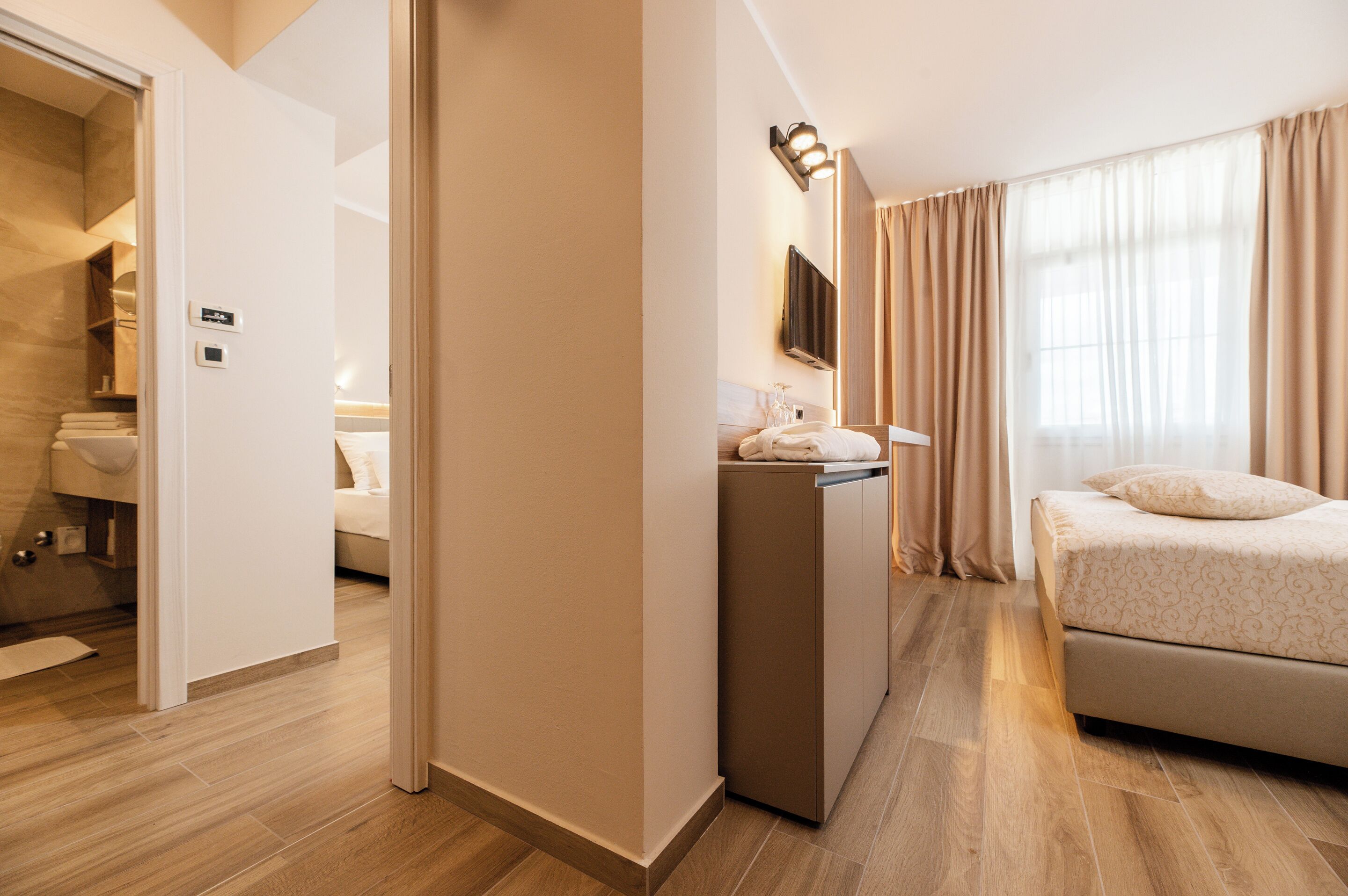 Ein Hotelzimmer mit Bett, Schreibtisch mit Lampe, Fernseher und angrenzendem Badezimmer.
