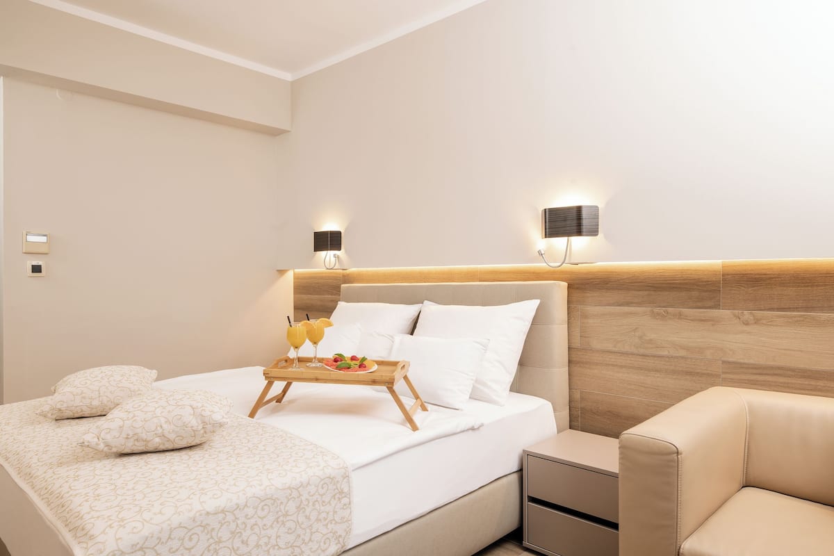 Une chambre d’hôtel moderne avec un lit bien fait, une table de chevet et un petit coin salon.