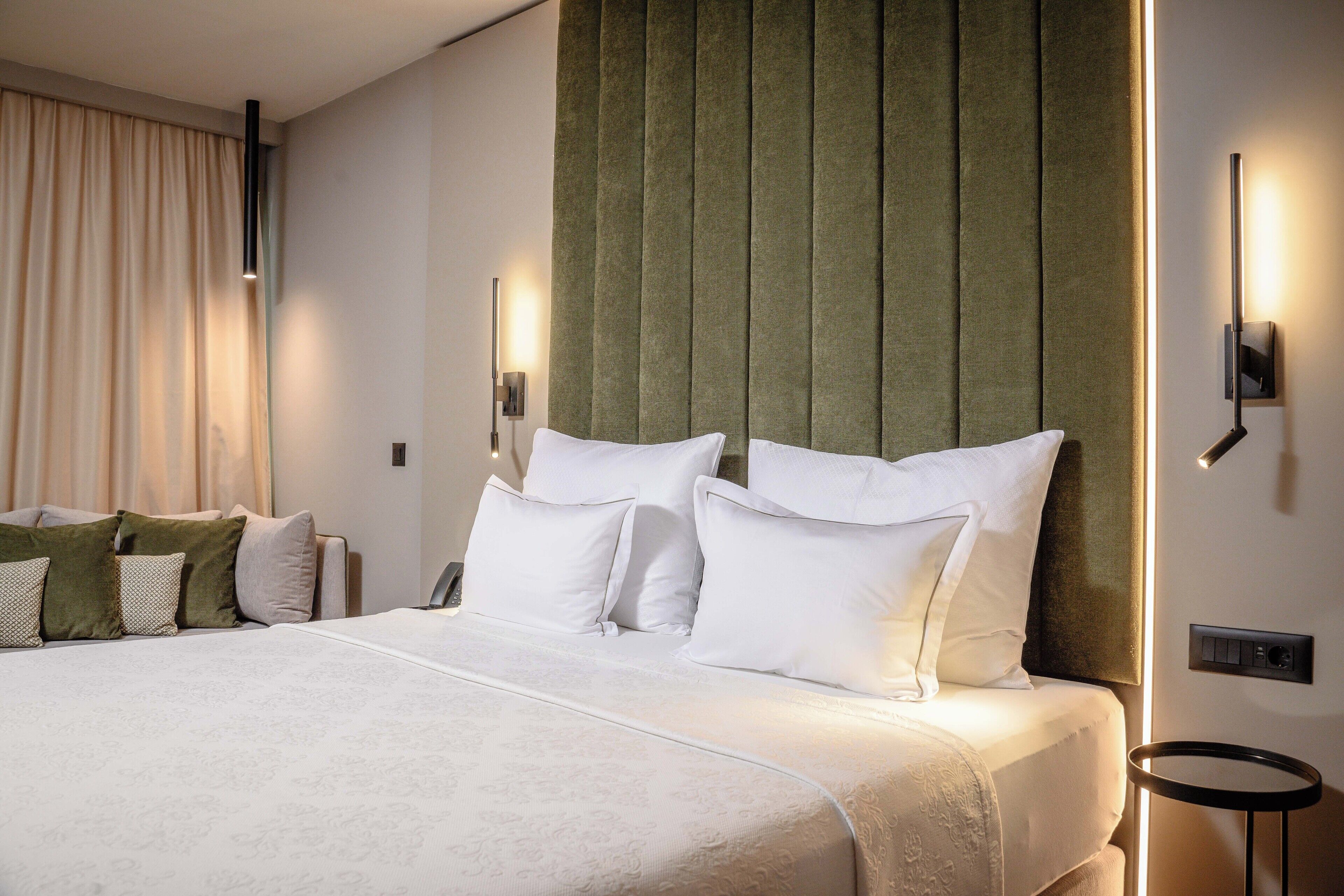 Ein Hotelzimmer mit einem großen Bett, einem Kopfteil mit vertikalen Paneelen und zwei Nachttischlampen.