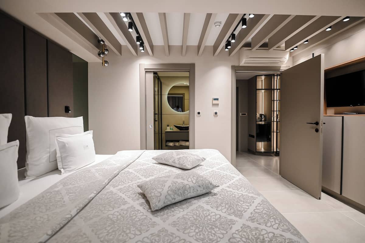 Une chambre à coucher moderne avec un grand lit, un dressing et un téléviseur fixé au mur.