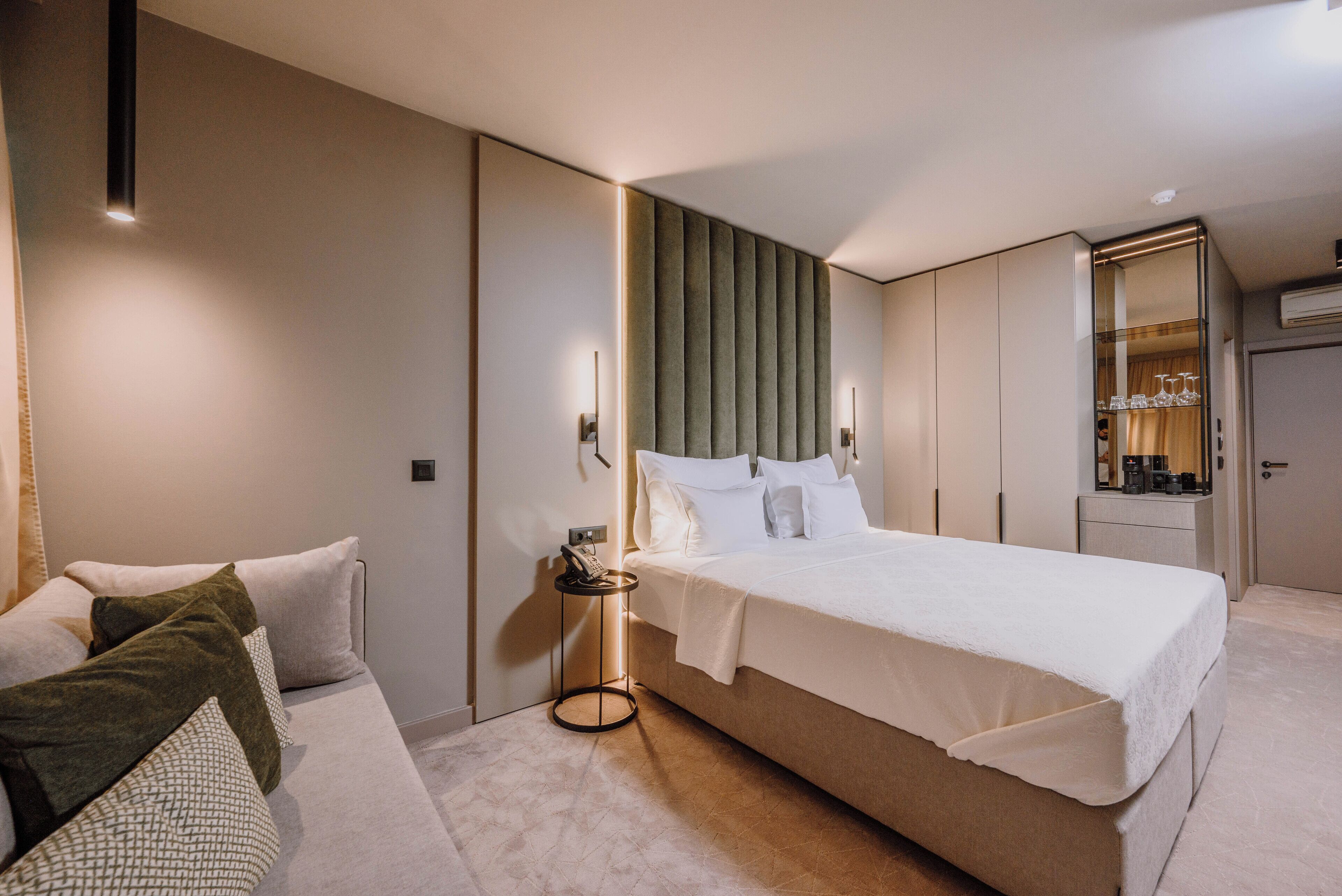 A modern bedroom with a large bed, a bedside table with a lamp, and a wardrobe.