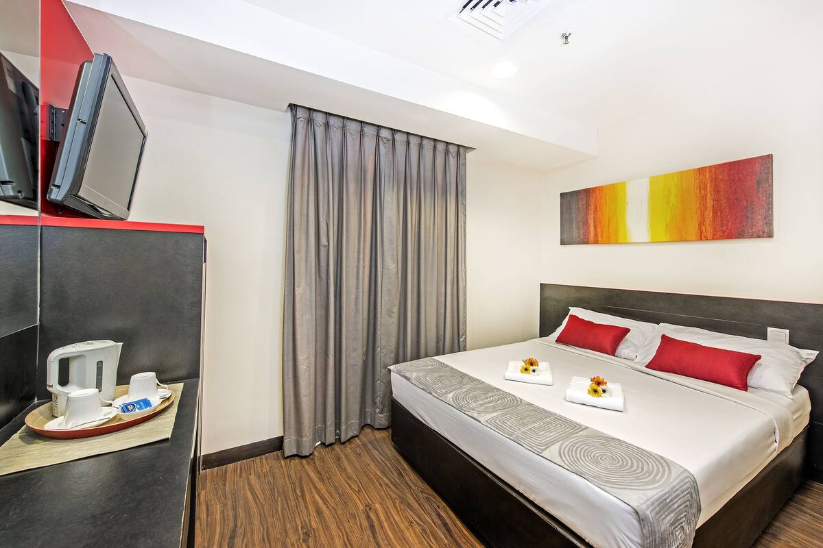 Ein Hotelzimmer mit Bett, Fernseher, Kaffeemaschine und einem Gemälde an der Wand.