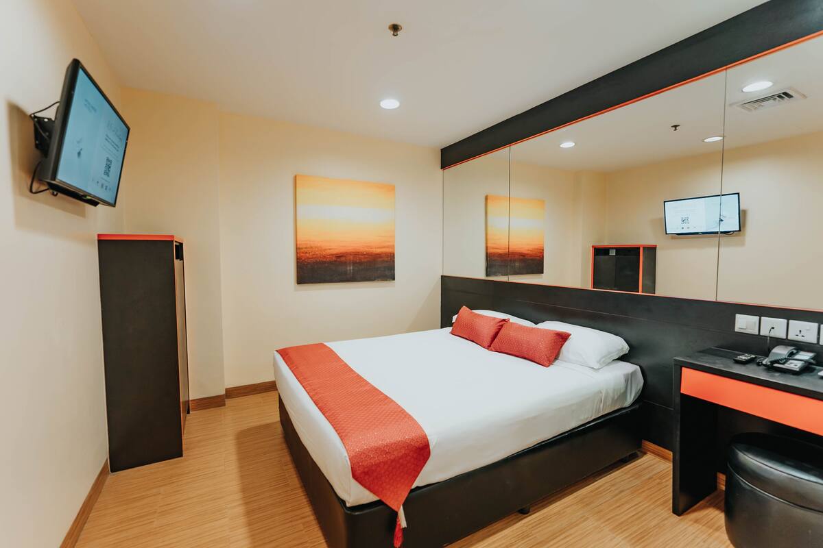 Ein modernes Hotelzimmer mit Bett, Schreibtisch und einem großen Spiegel.