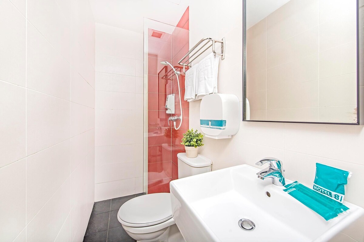 Een moderne badkamer met een wit toilet, een wastafel met spiegel, en een douchehoek.