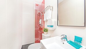 Une salle de bain moderne avec des toilettes blanches, un lavabo avec un miroir et un espace douche.