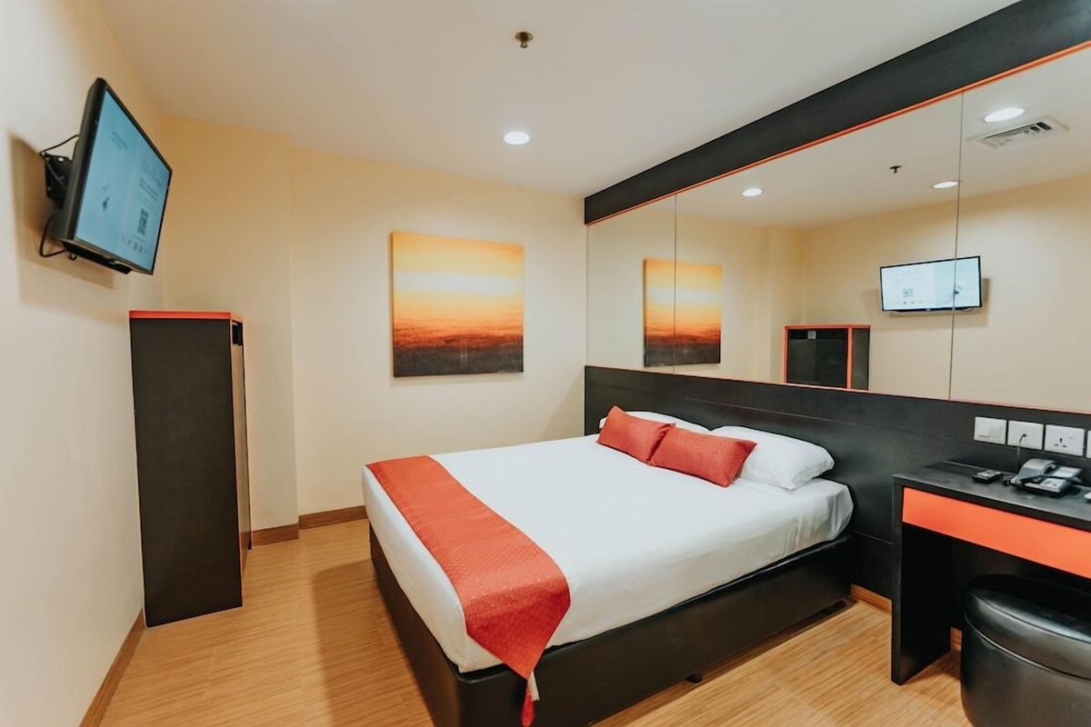 Une chambre d’hôtel moderne équipée d’un lit, d’un bureau, d’un miroir et d’œuvres d’art accrochées aux murs.