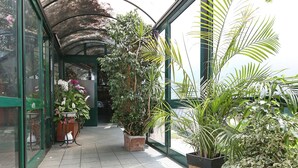 Un paseo techado con plantas en macetas y una mesa adornada con flores.