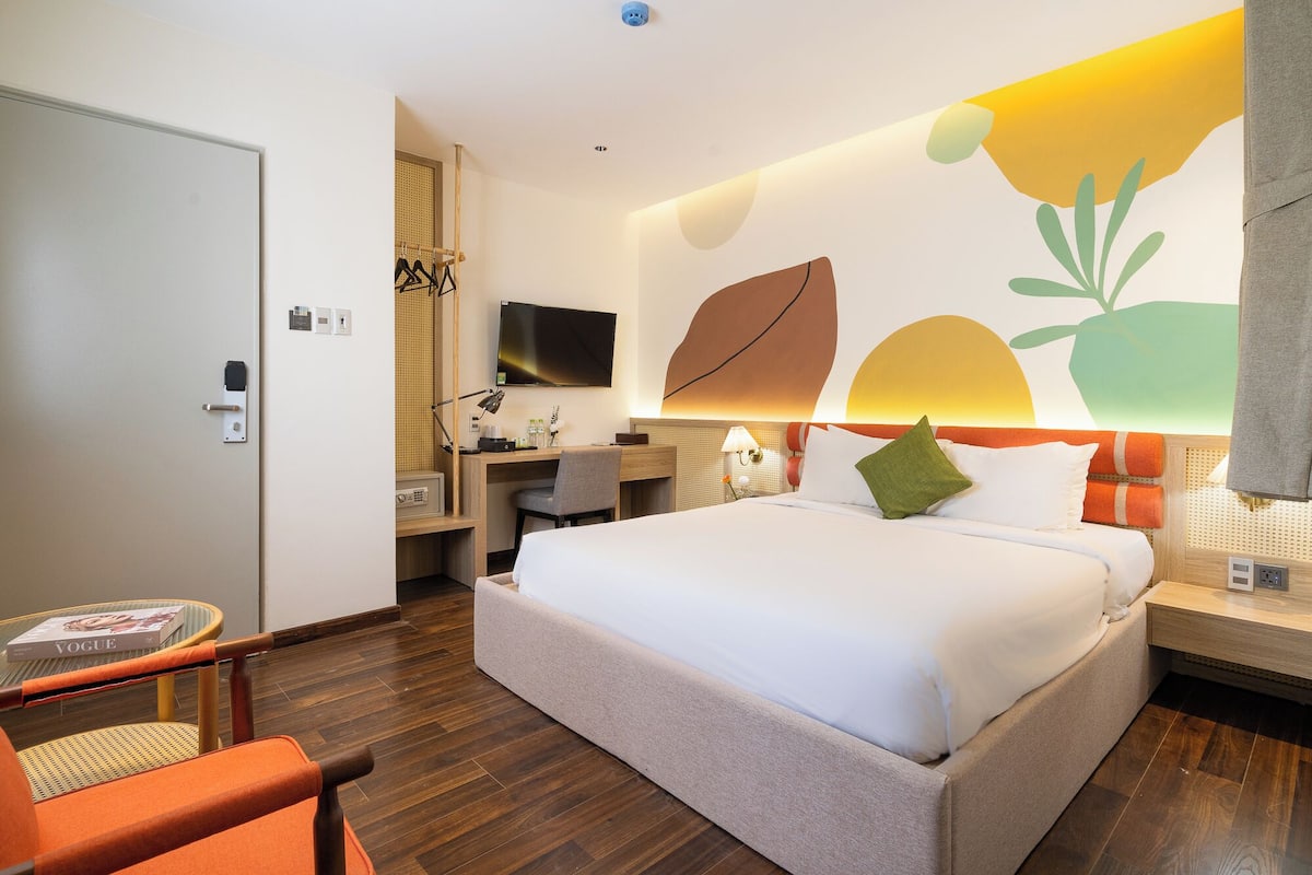 Een hotelkamer met een bed, bureau, stoel en een televisie aan de muur.