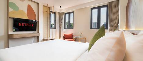 A hotel room with a large bed, a TV mounted on the wall, a small table, and a chair.