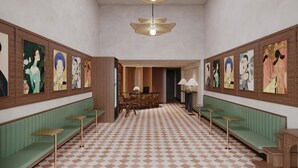 Un hall de hotel con piso a cuadros, asientos acolchados verdes y obras de arte colgadas en la pared.