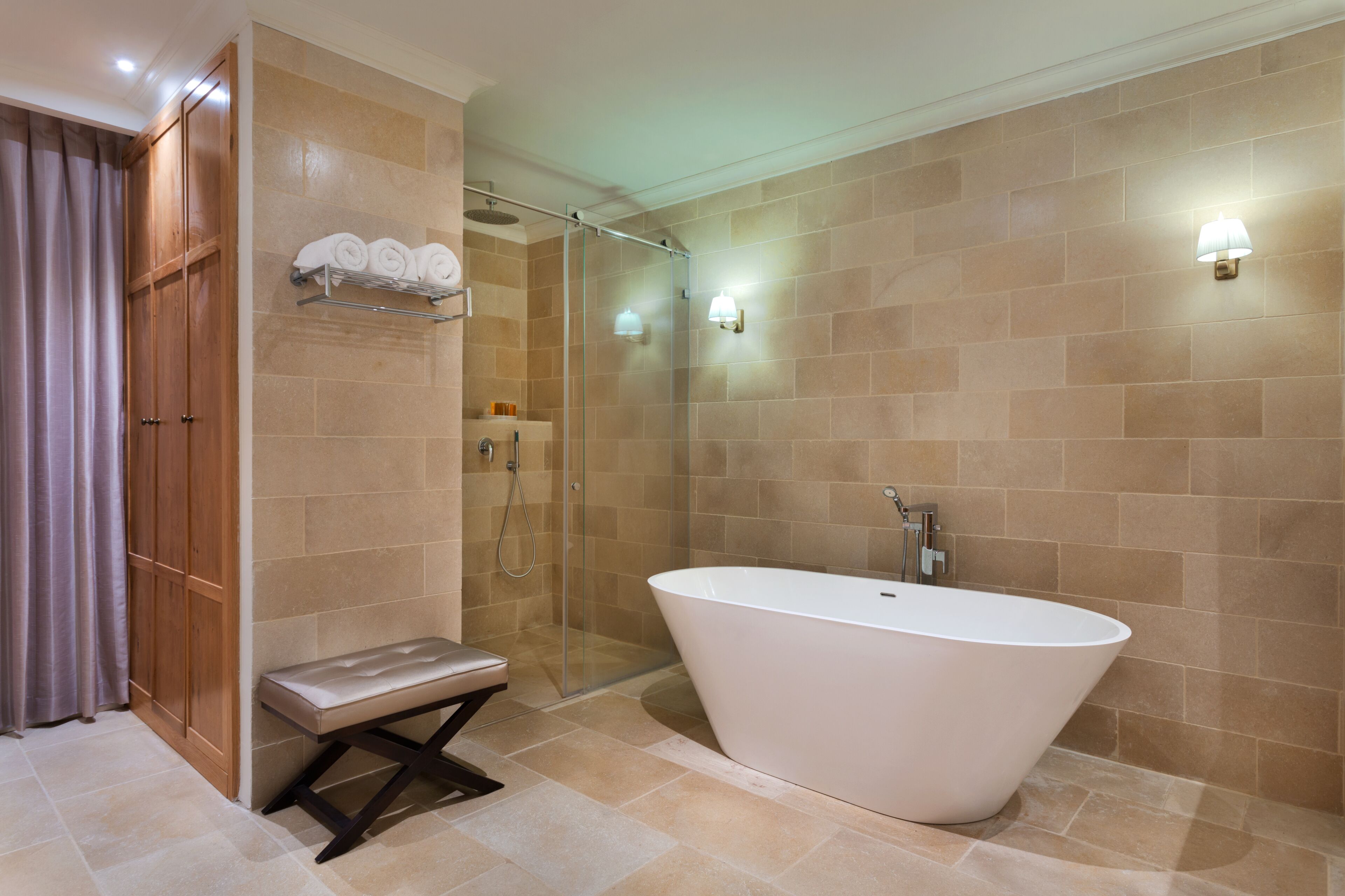 A modern bathroom with a freestanding bathtub, a glass-enclosed shower, and a bench.
