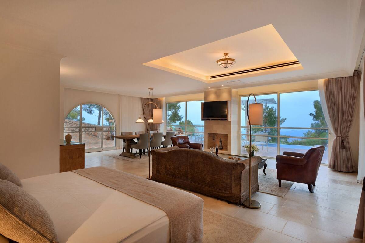 A spacious room with a large bed, a dining area, and a fireplace.