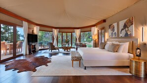 A spacious bedroom with a large bed, a wooden floor, and a view of the outdoors.